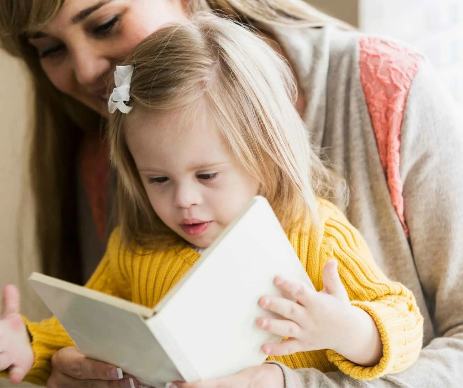 parent and toddler with Down syndrome reading together