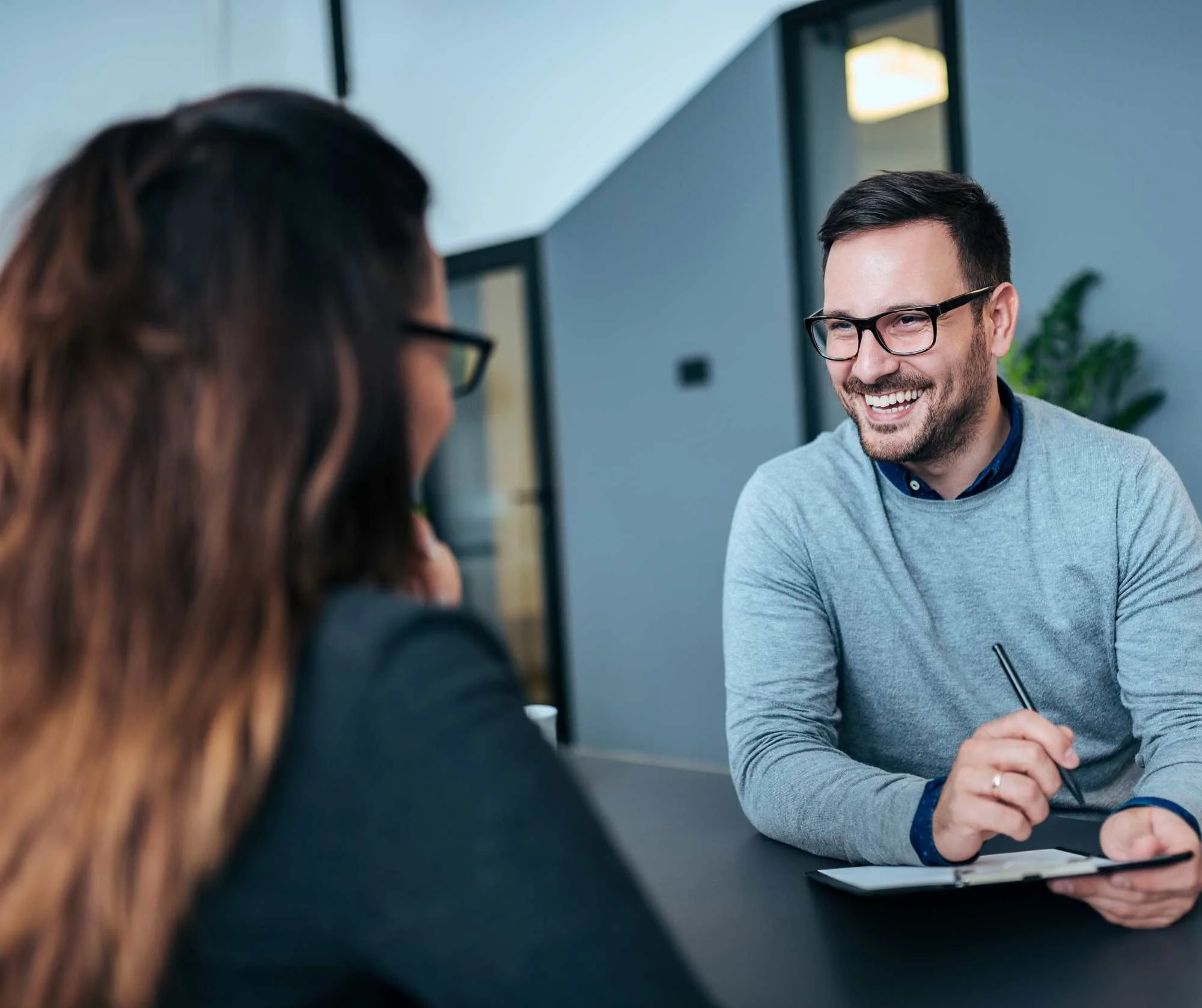 Smiling man in glasses talking with a woman across a table