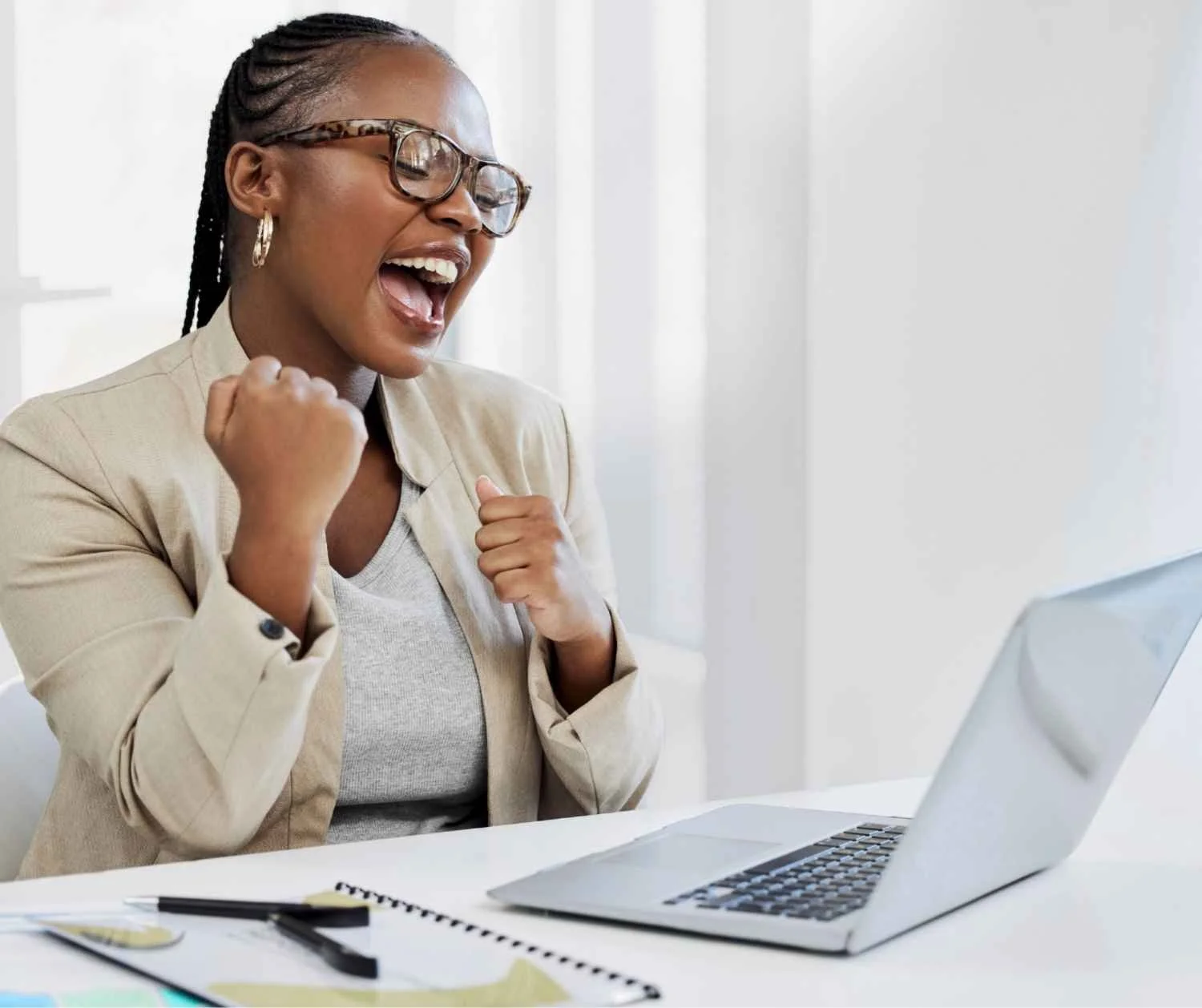 Woman cheering at her laptop in a home office.