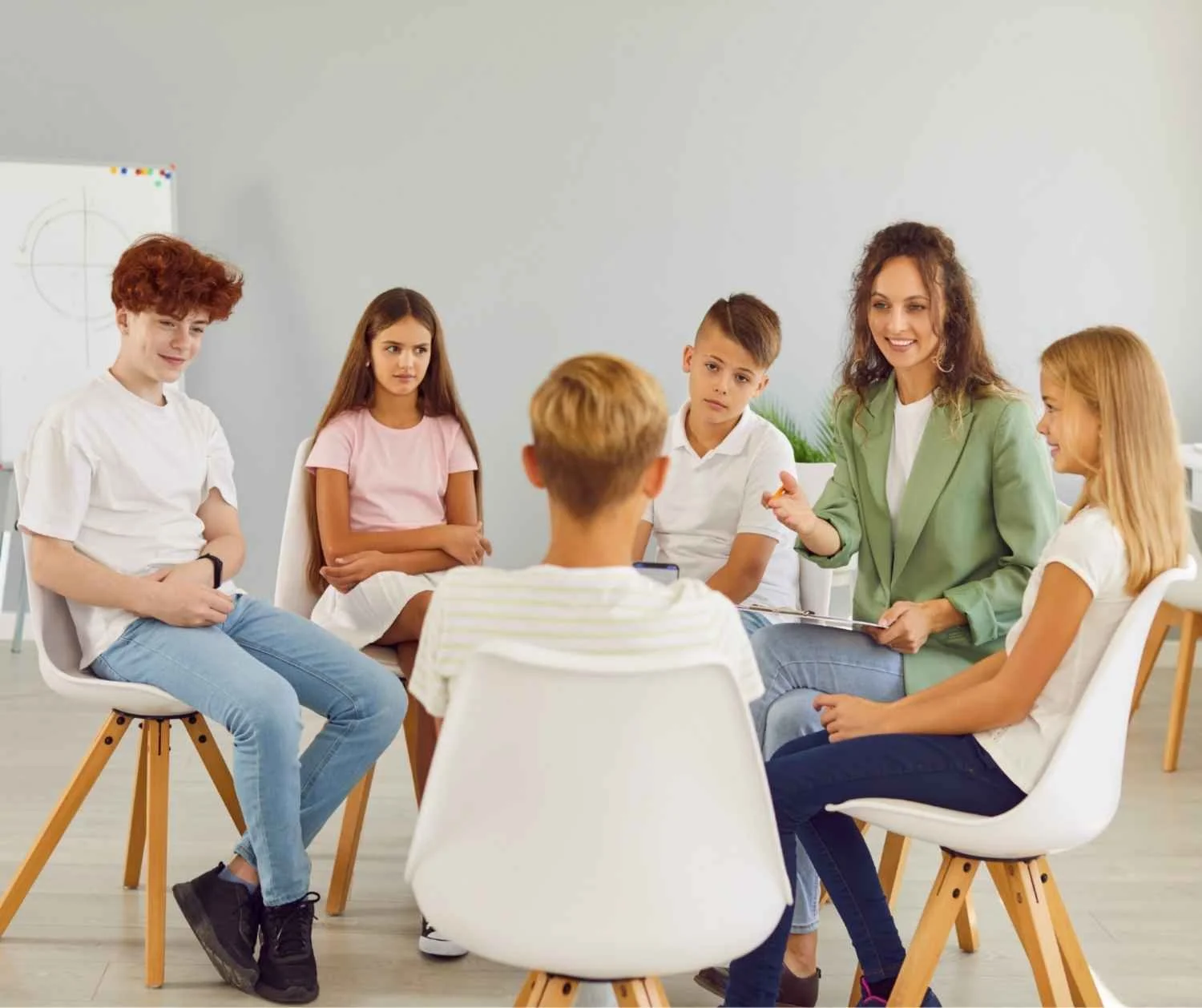 Small group of children sitting in a circle talking with an adult.