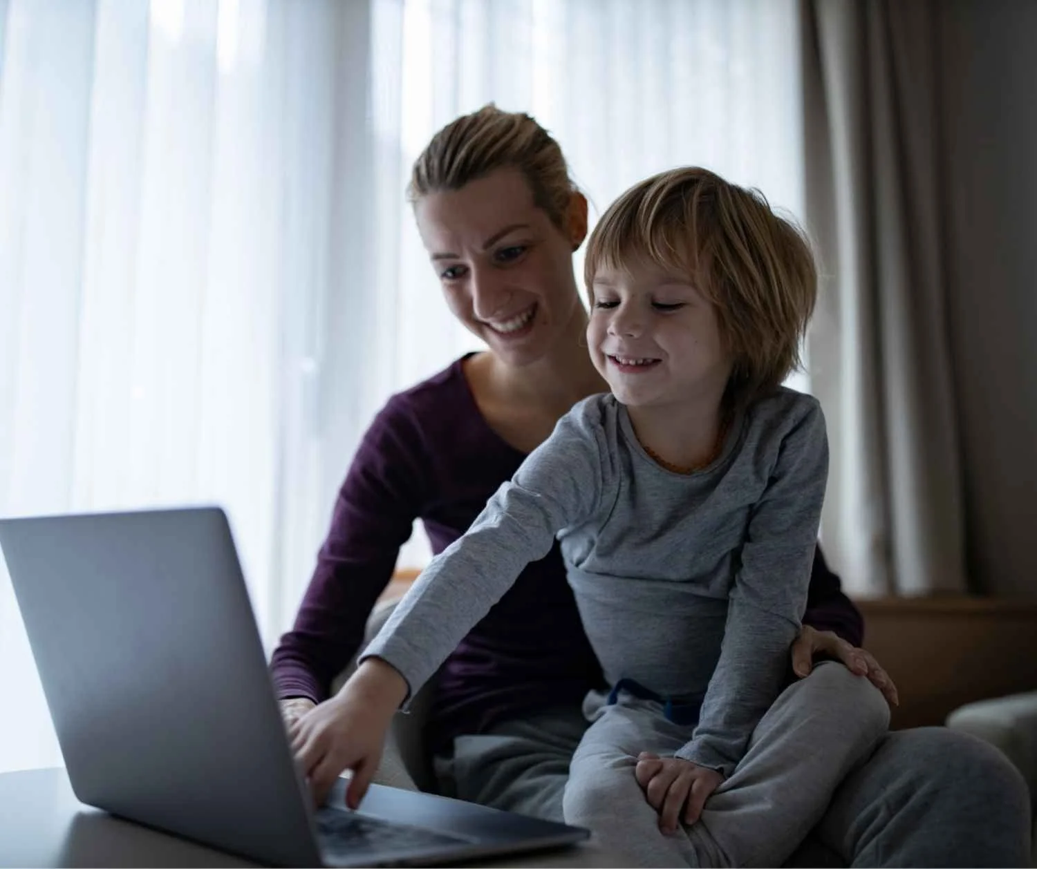 Mother sitting beside her young son on the laptop