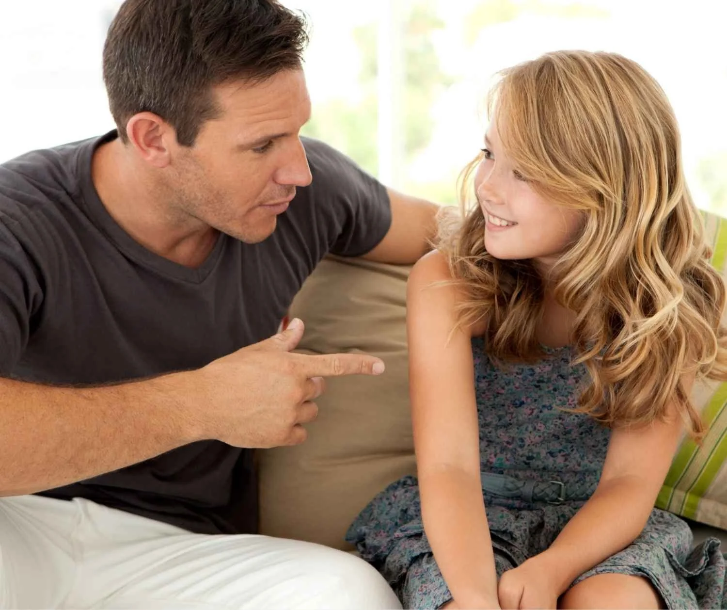 Girl talking to her father while they sit together in the living room.