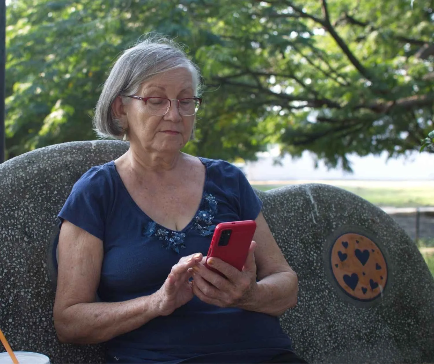 Older woman reading aloud while checking a volume app on her phone