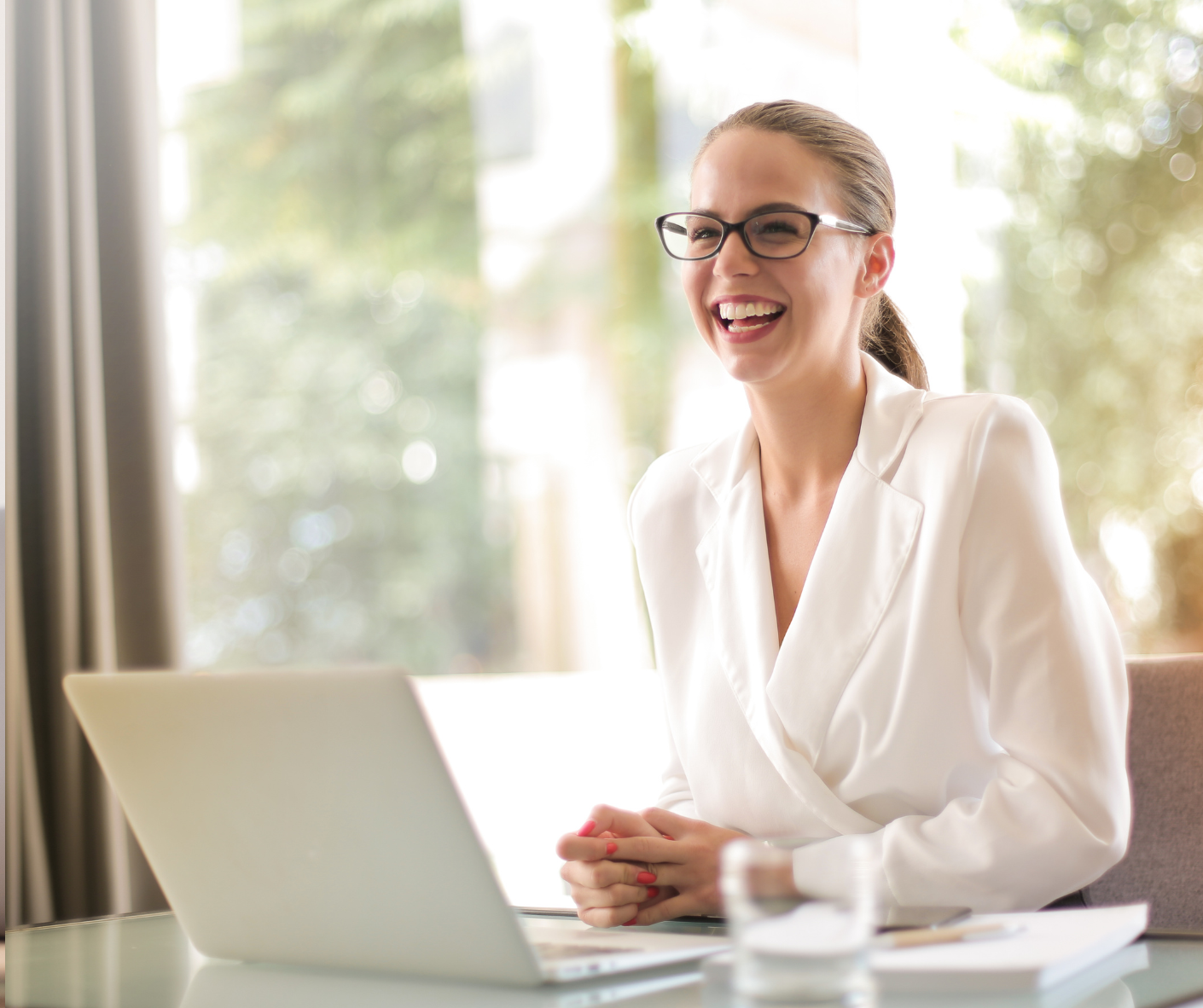 Smiling professional in a white blazer during an online coaching session at her laptop