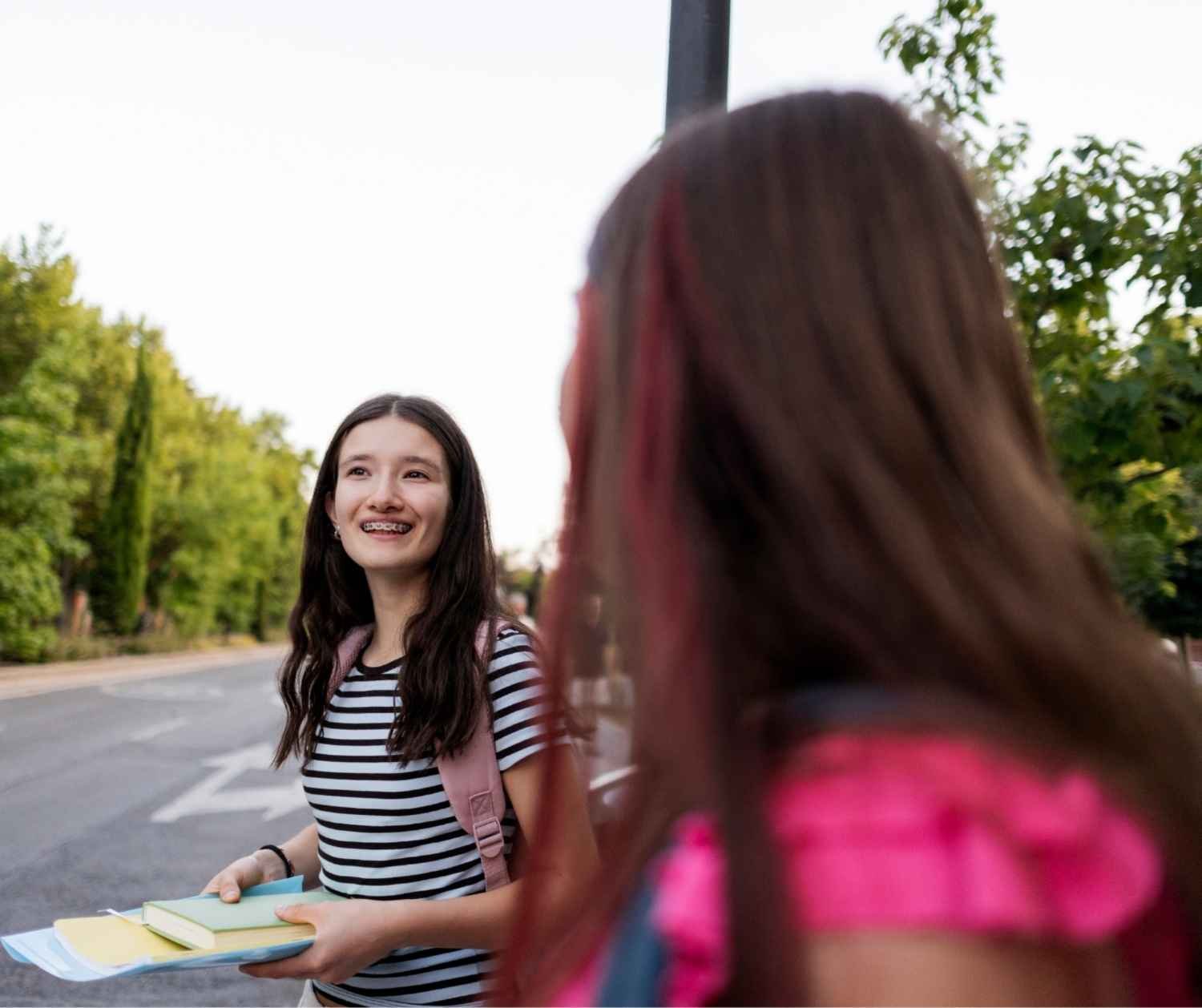 Two children walking home from school, one talking while the other looks away