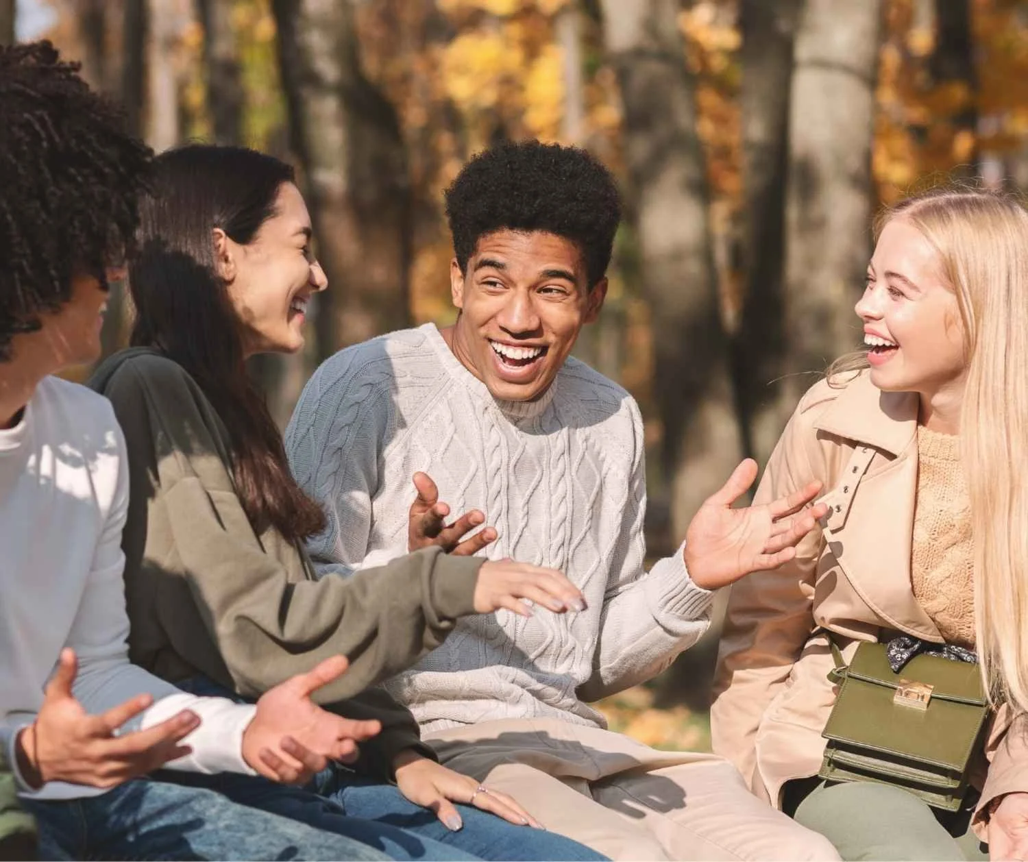 Teenagers talking and laughing with friends on a park bench