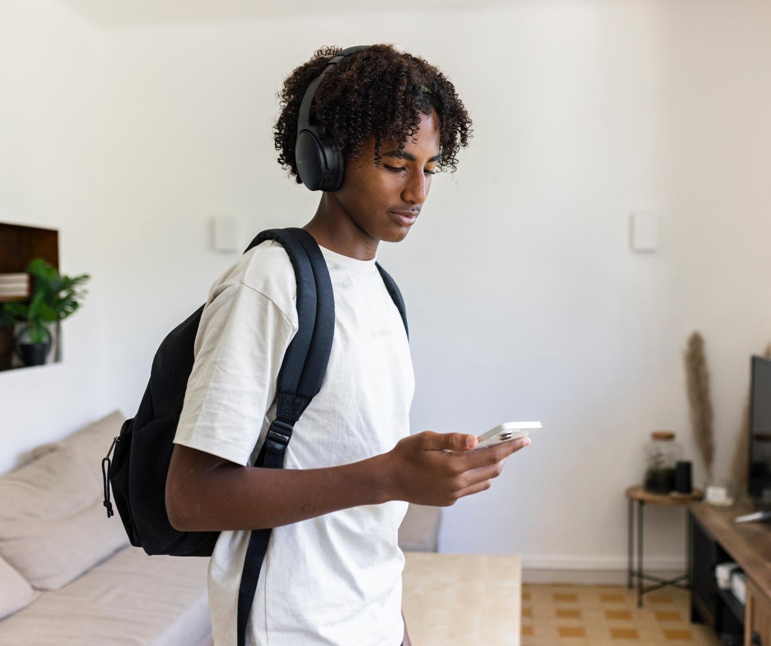 Teen with headphones looking at his phone