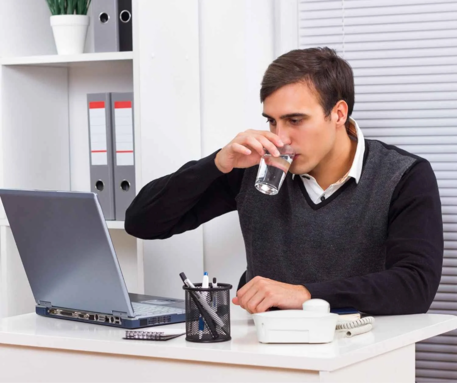 adult drinking water glass at desk