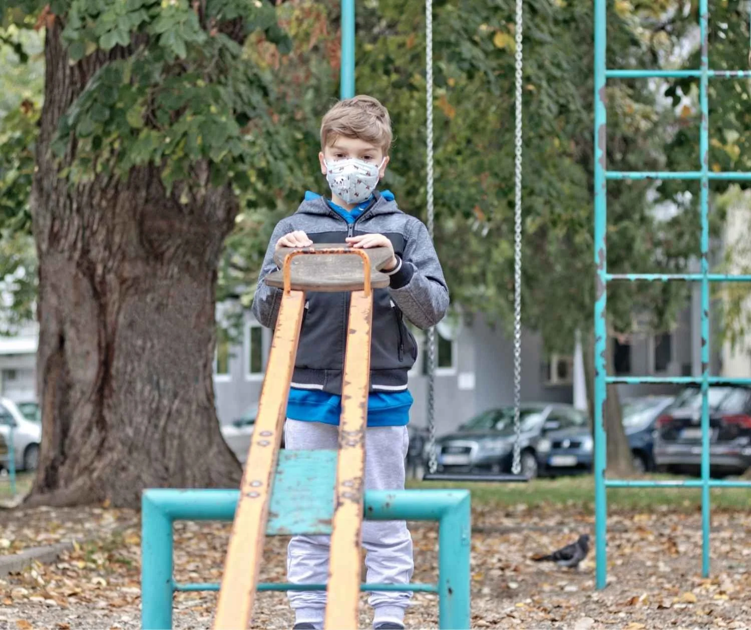Boy standing at the edge of a playground while a group of kids plays without him