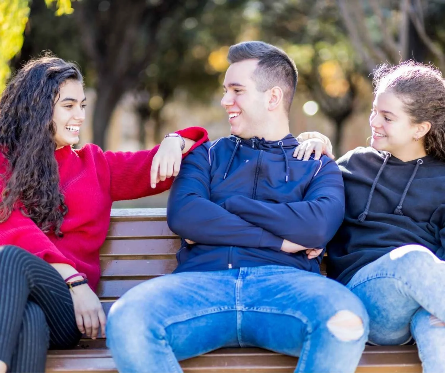 Three friends talking and laughing on a park bench