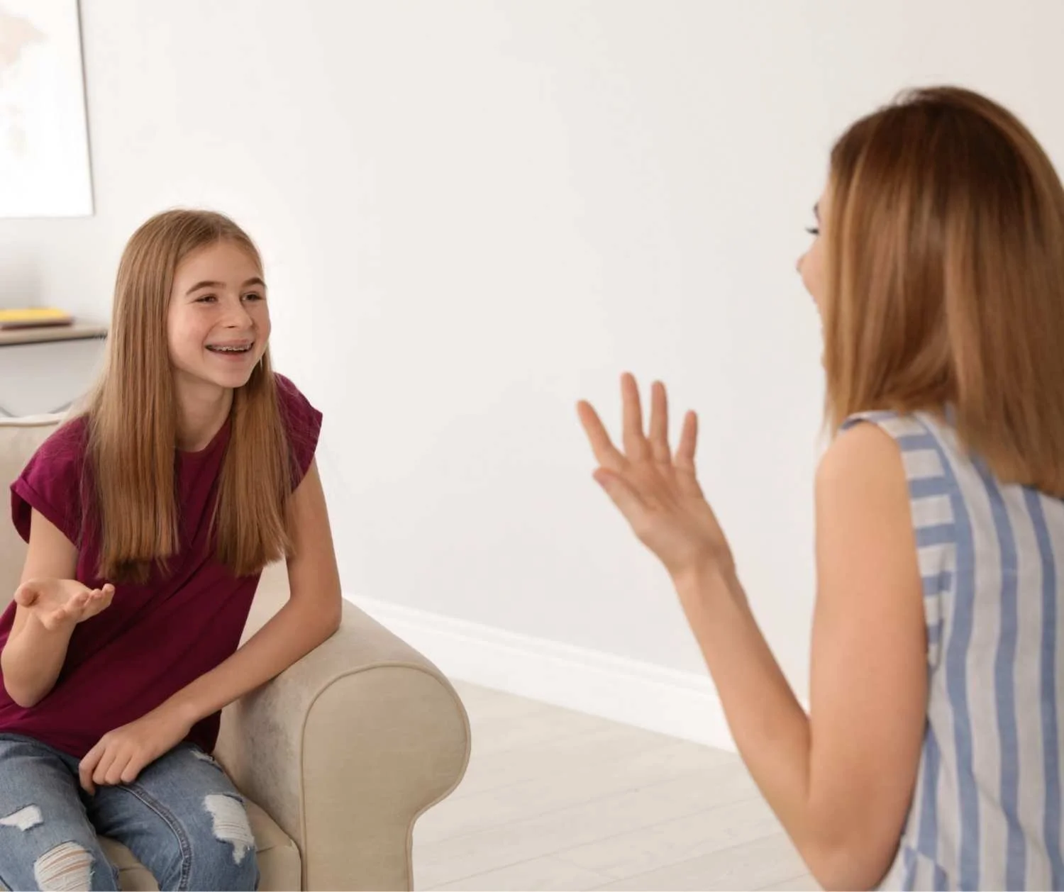 Mother watching her daughter talk at the couch