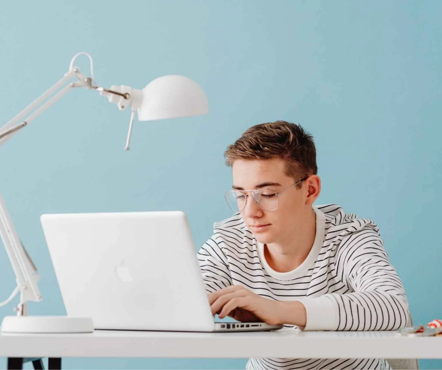 Teenage boy taking part in a live online speech therapy session on a laptop.