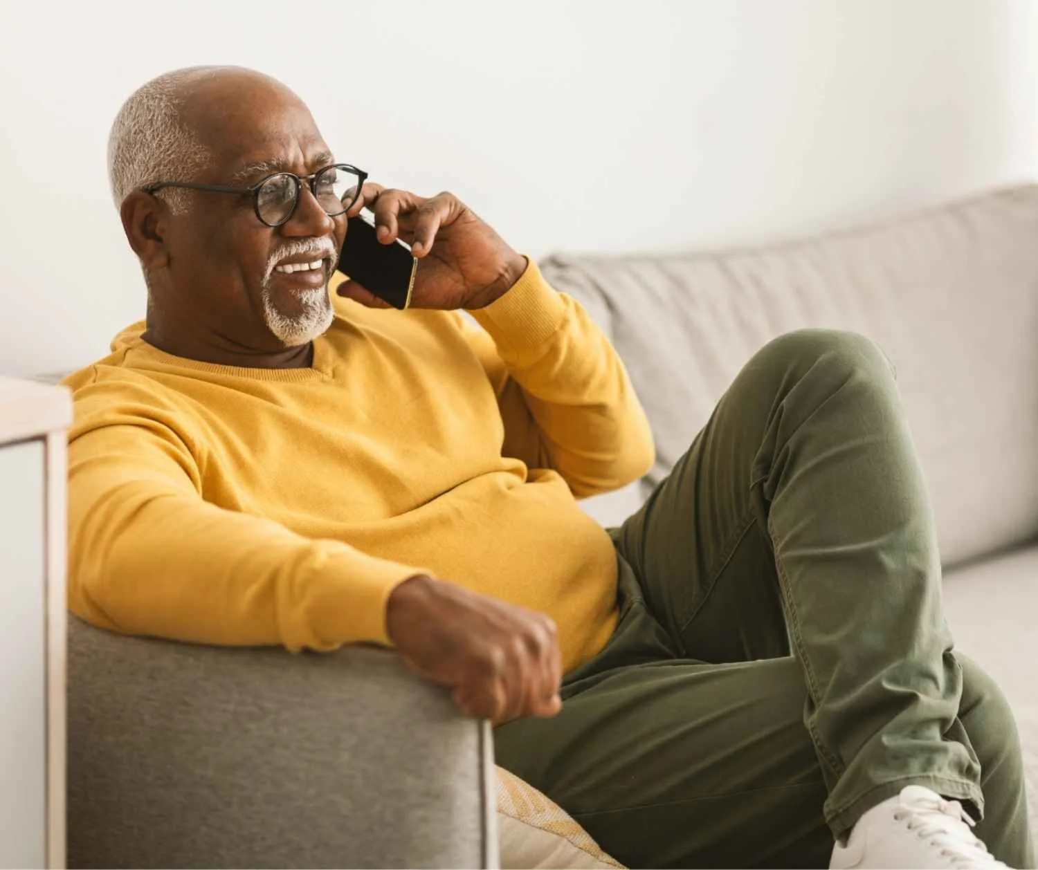 Older man smiling while talking on the phone at home