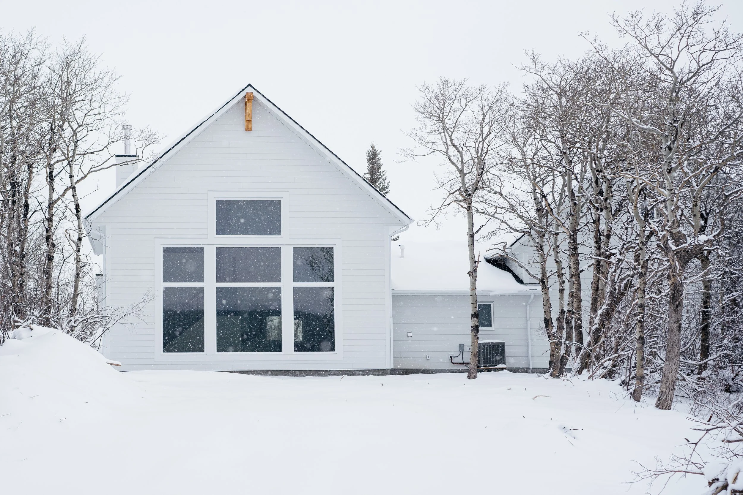 A white house surrounded by snow-covered ground and leafless trees in winter.