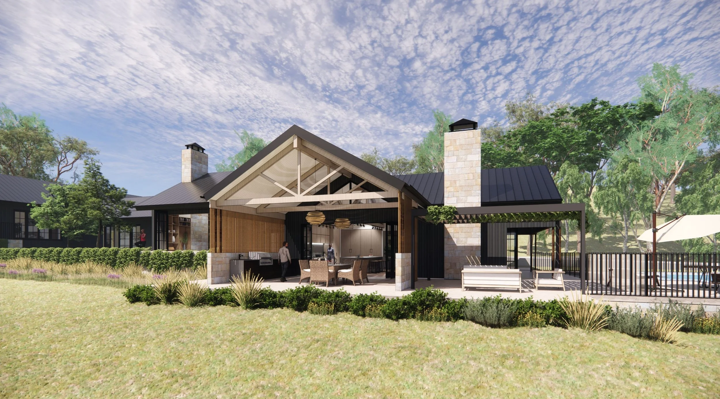 A modern outdoor pavilion with a gabled roof and stone chimneys, surrounded by greenery and trees, with a grassy yard and a sitting area with chairs and a table.