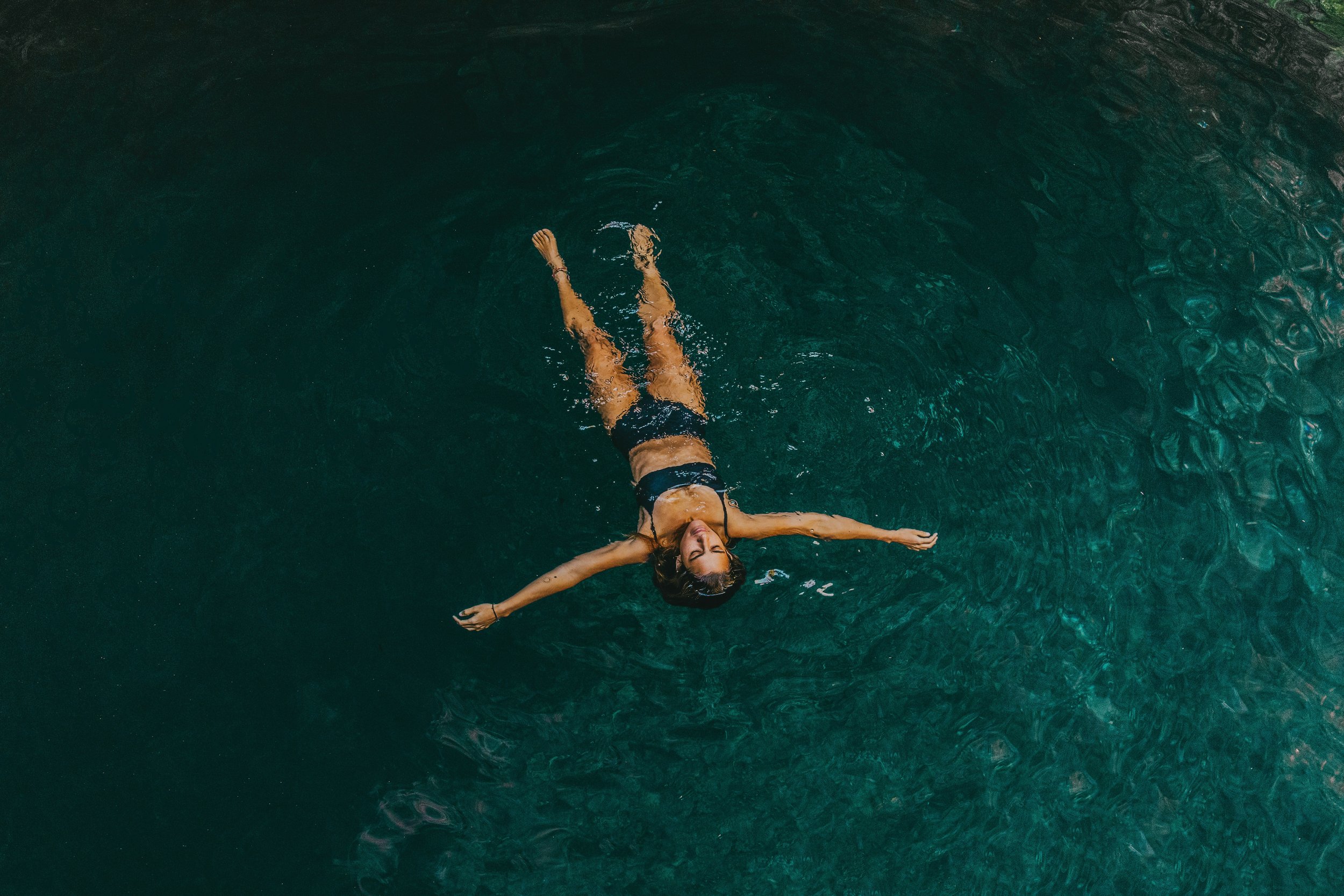 Woman in a bikini floating in a pool of tranquil water