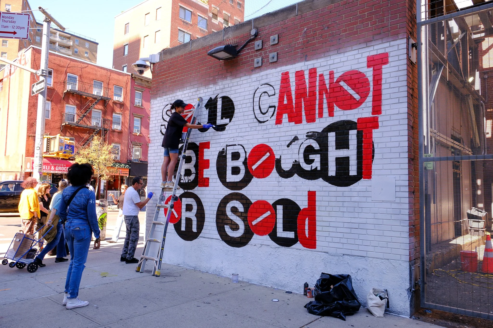 Al Diaz and Mariah Fox Hausman work on his mural at the corner of Avenue A and E. 5th Street in the East Village. Photo by Jamie Lubetkin
