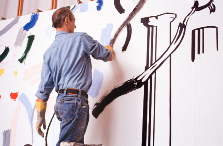 Roy Lichtenstein applies a diagonal brushstroke to the unfinished canvas of Forest Scene with Temple in his Southampton studio, circa 1986.