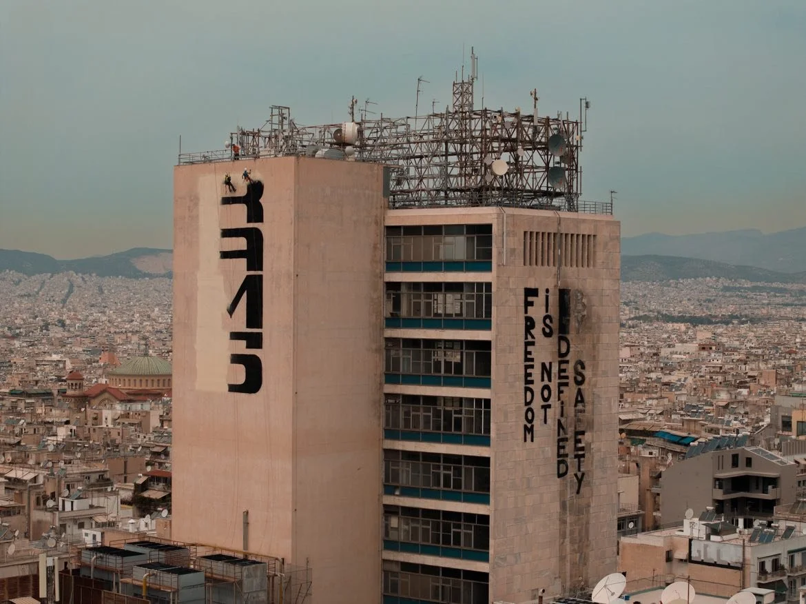 RAMS and other rappel graffiti writers working on the side of a highrise in Athens.