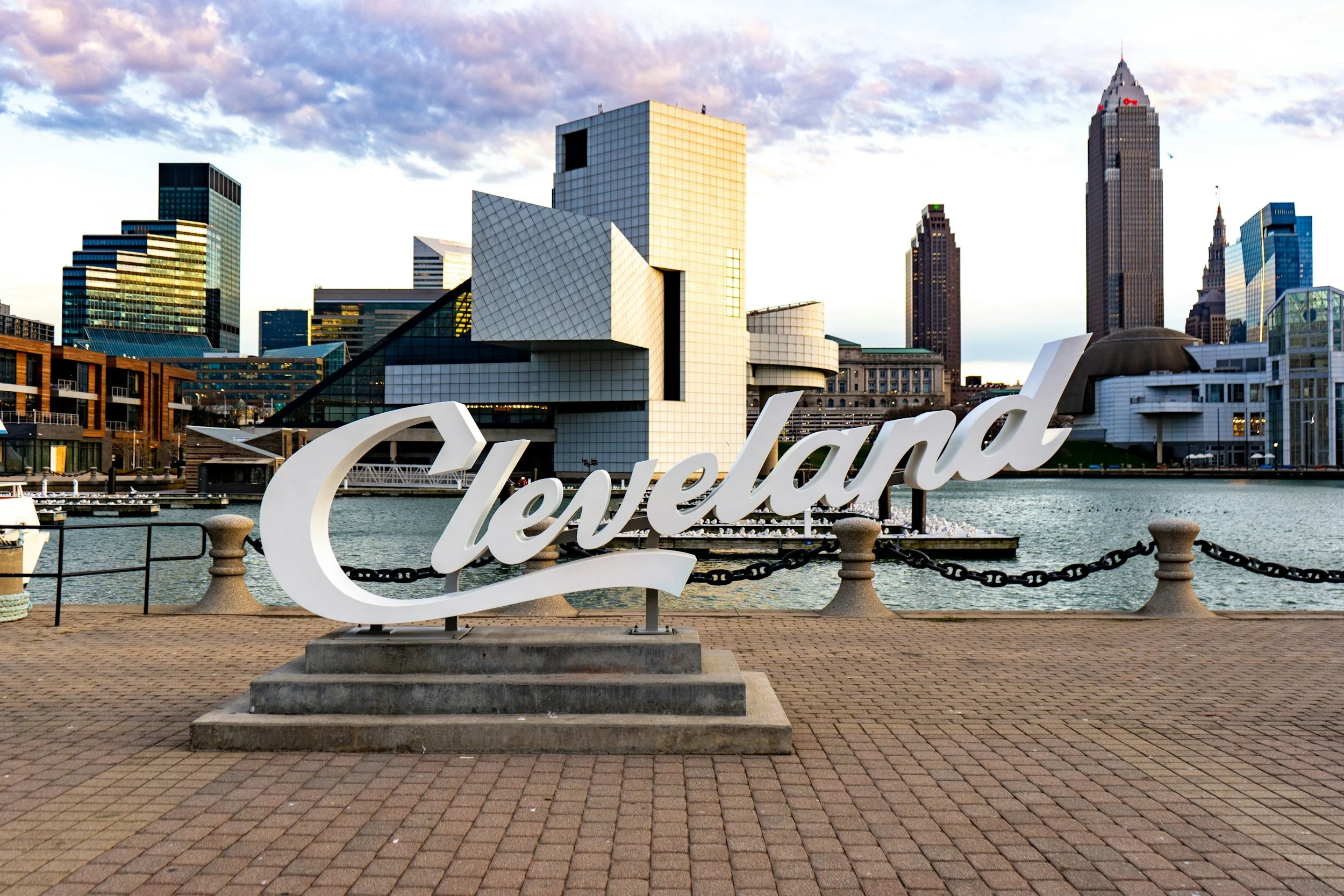 Cleveland city skyline with a waterfront view and the Cleveland sign in the foreground.