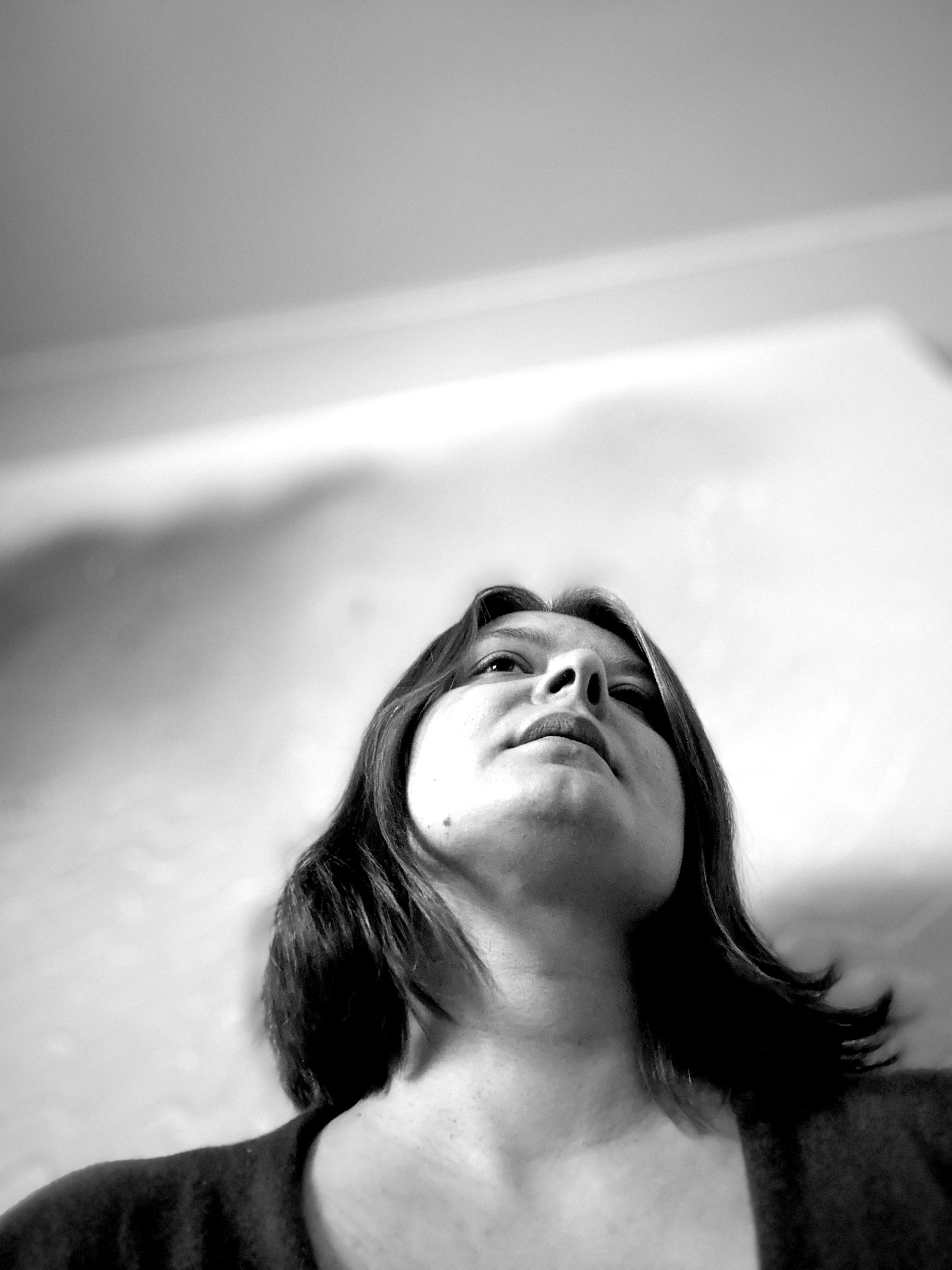 Black and white photo of a woman looking up, with her face partially visible and her hair falling on her shoulder.