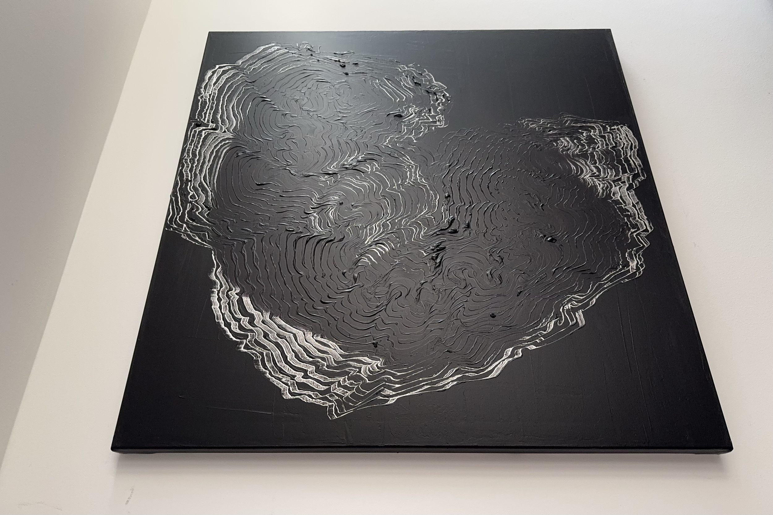 Abstract artwork on a black canvas with swirling, layered metal lines creating a topographic or geological pattern.