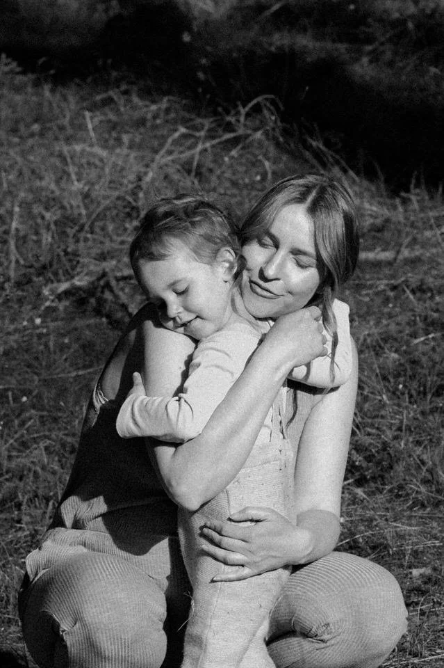 Mother hugging her child during a family photo session in woods