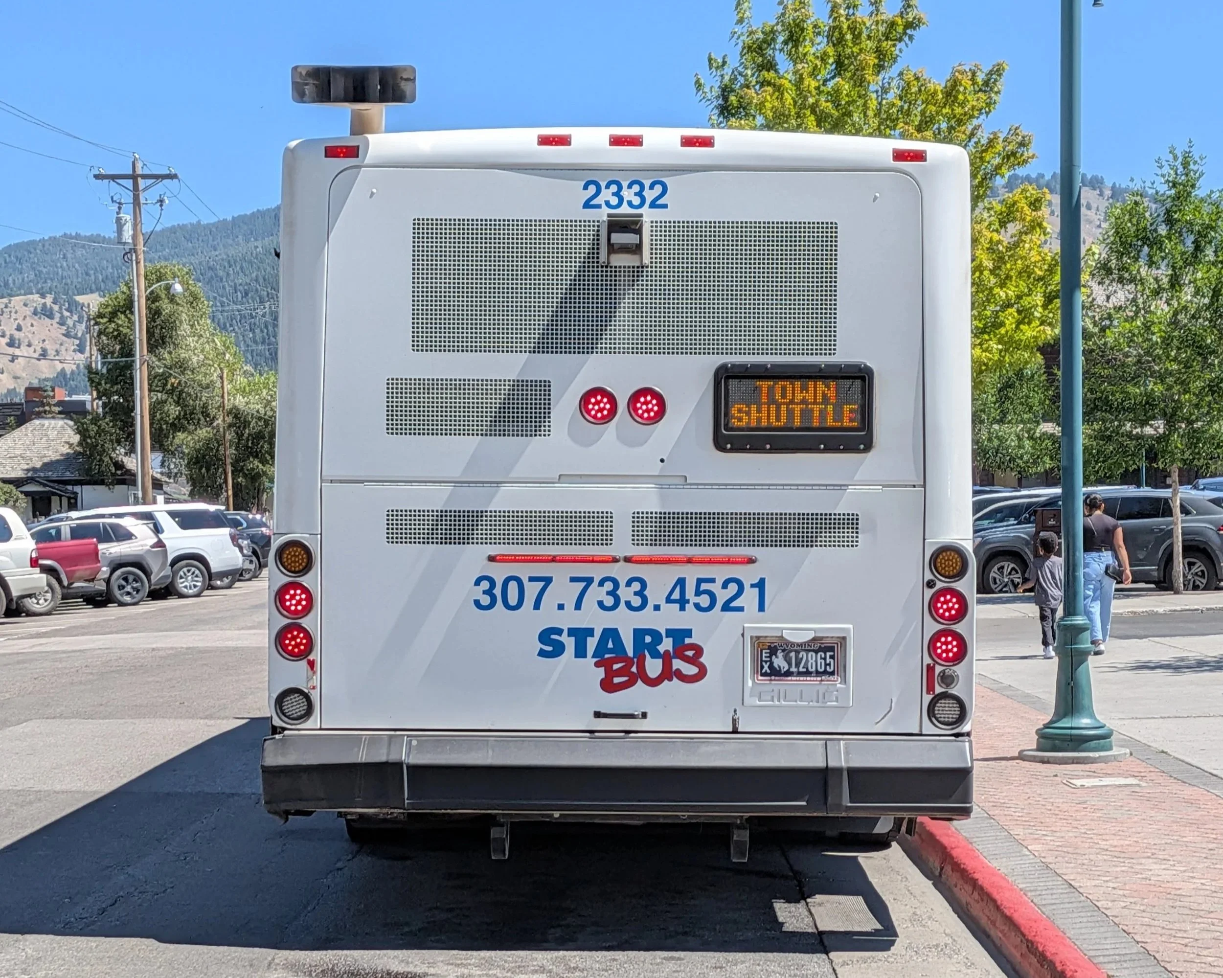 An image of the back of a large white bus that says "START bus 307-733-4821" and a marque that says "Town Shuttle"