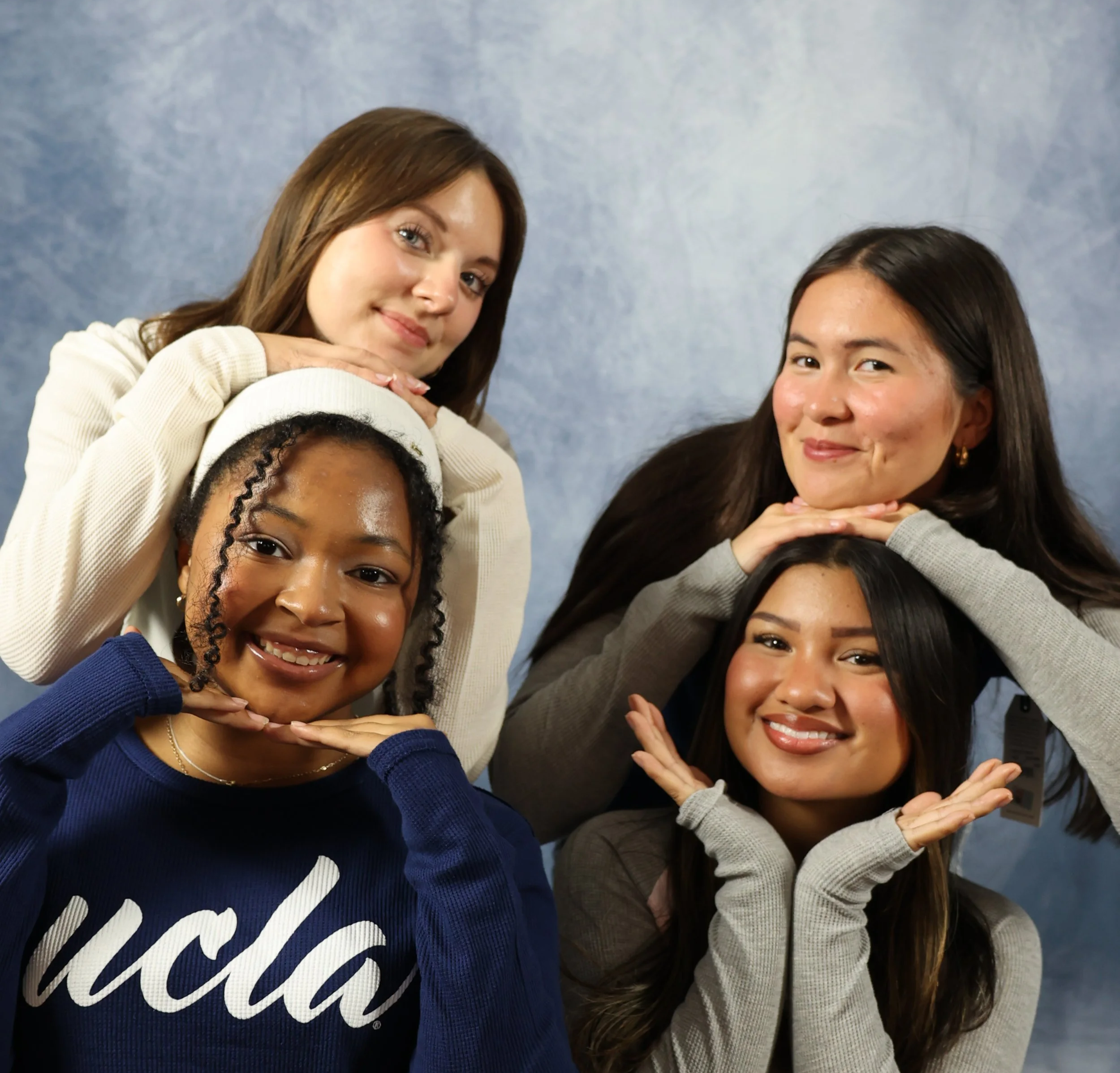 Four women pose in front of a blue backdrop