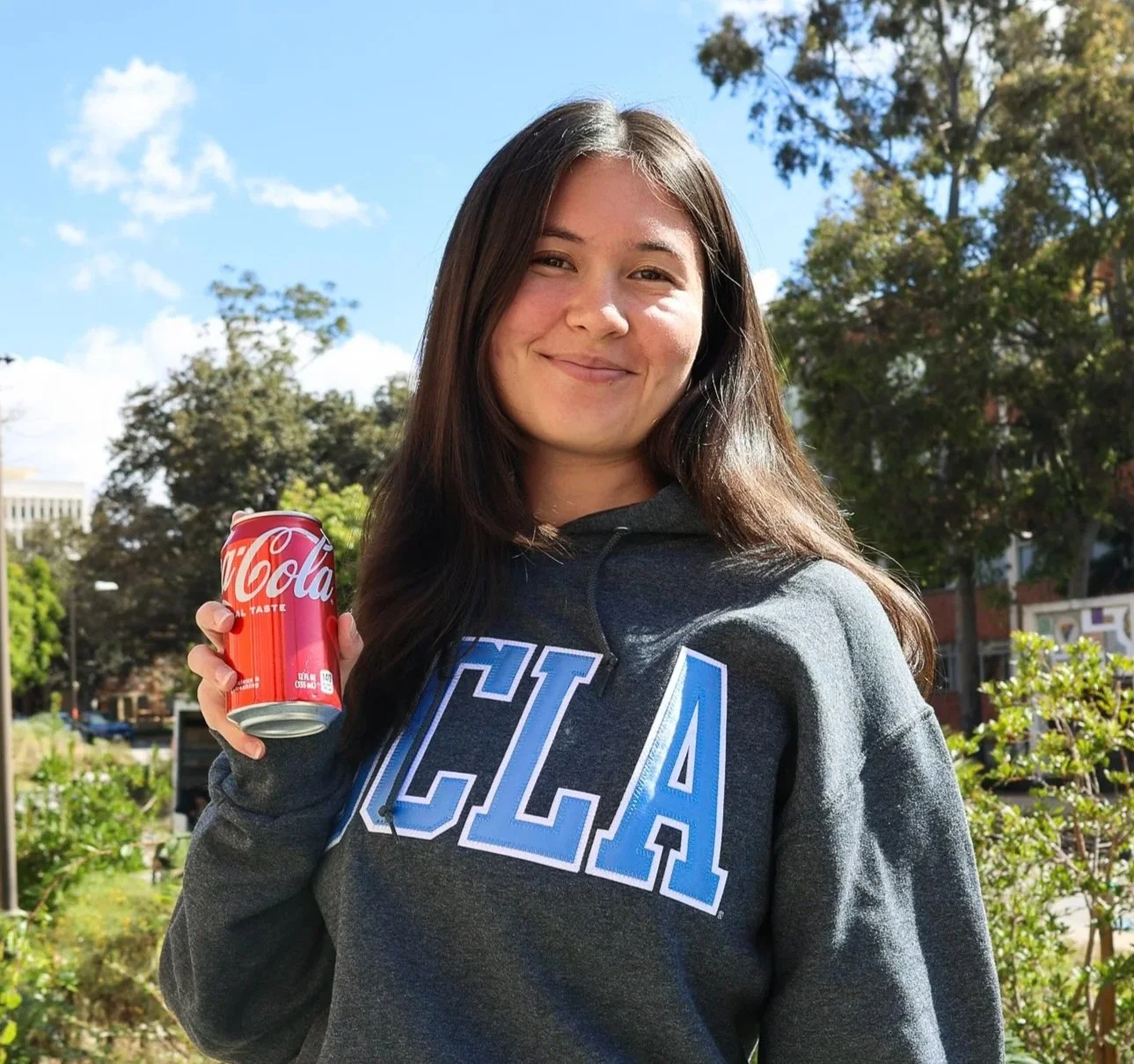 Woman poses in UCLA hoodie with red Coca Cola can