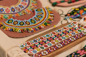 Close-up of colorful handcrafted beaded jewelry and traditional beaded collars displayed on a table.