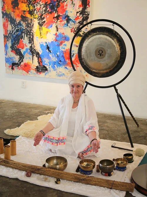 Instructor leading a sound bath meditation session with singing bowls and a gong in a calming indoor space