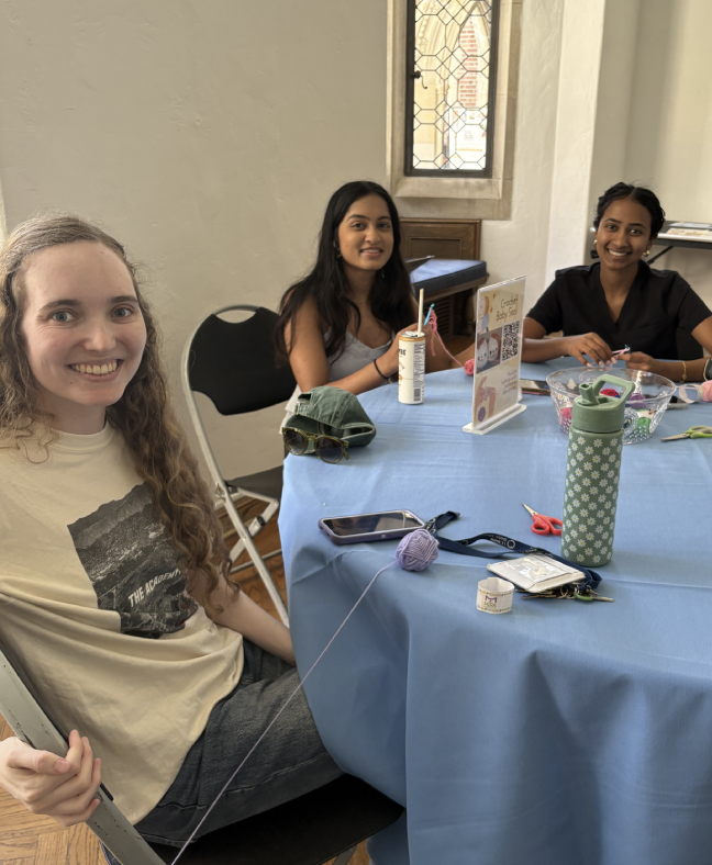 Three young women sitting at a table with crafting supplies, smiling for the camera.