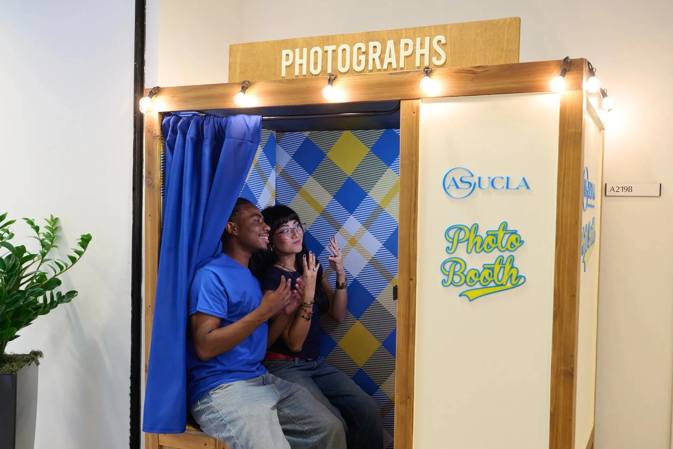 A man and women holding four fingers up on each hand, posing for a photo in a photobooth.