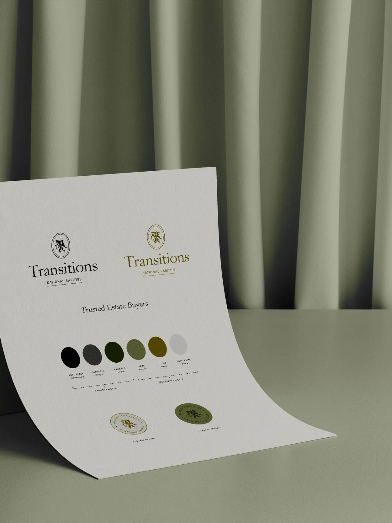 Printed brochure displaying color options and logos for Transitions, a brand for trusted estate buyers, placed on a flat surface with a light-colored curtain in the background.