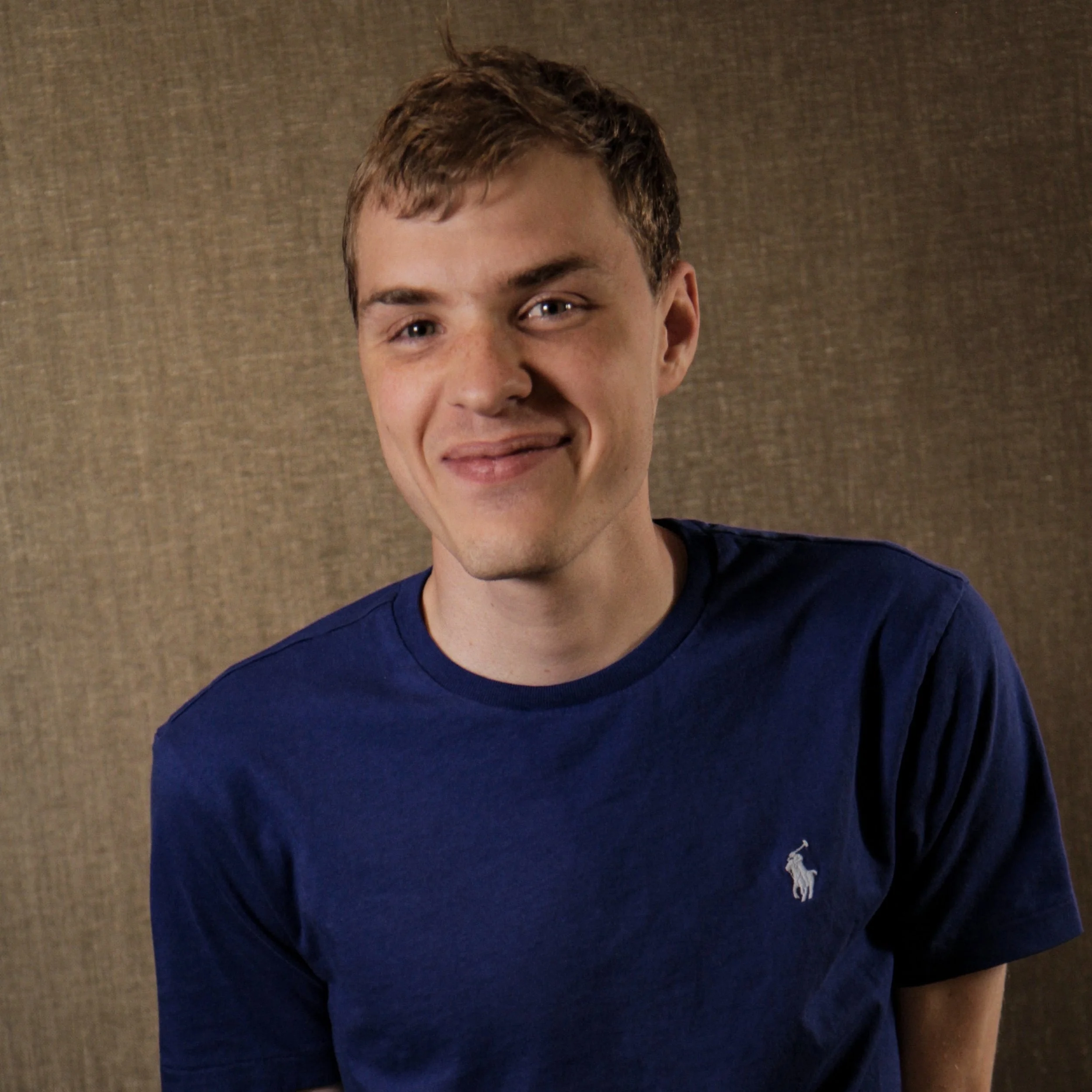 Person wearing a blue shirt against a textured background.