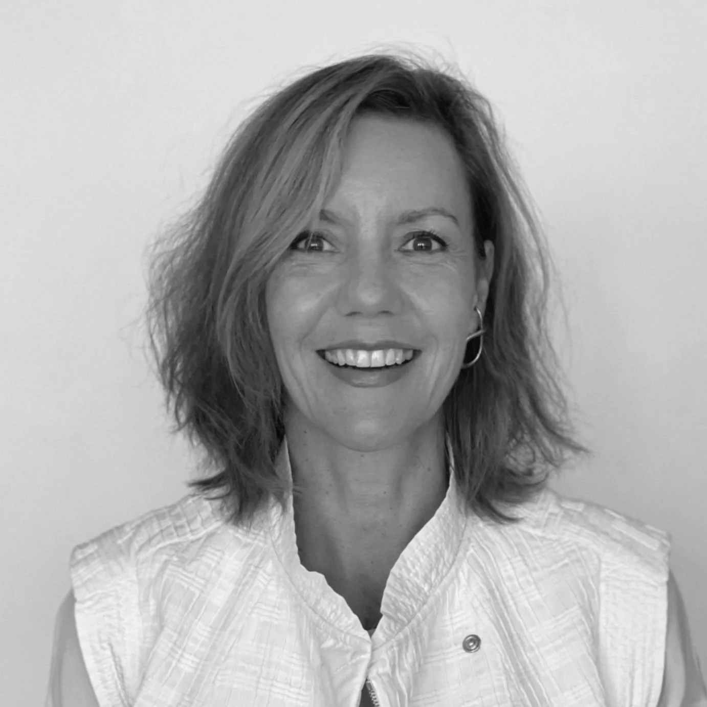 Portrait en noir et blanc d'une femme souriante portant une chemise à boutons.