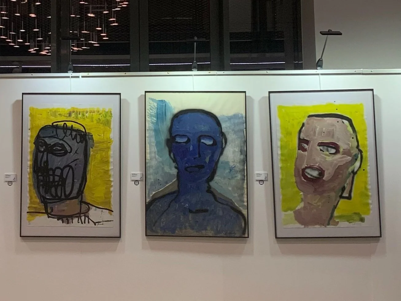 Trois peintures abstraites de portraits humains dans une galerie d'art