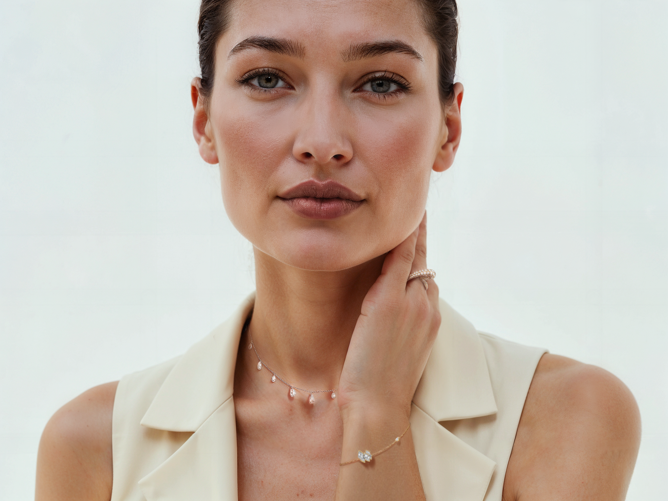 Portrait d'une femme avec cheveux bruns, yeux gris, portant des bijoux fins, une veste blanche sans manches, contre un fond blanc. Mannequin Virtuel IA par Artcare