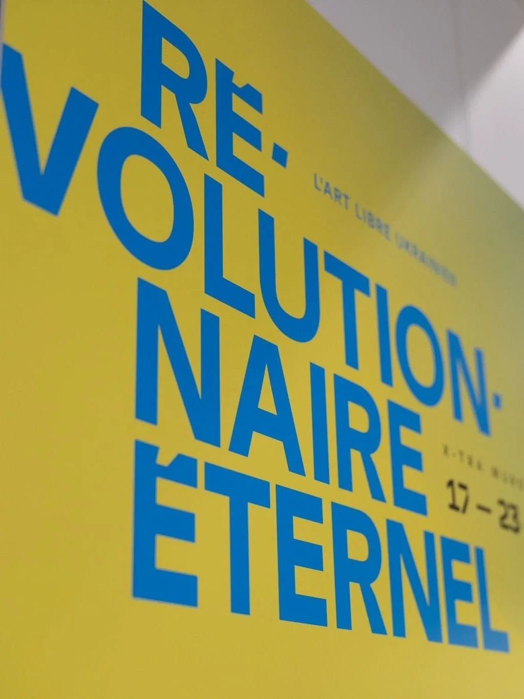 Affiche d'une exposition artistique avec texte en français en bleu sur fond jaune.
