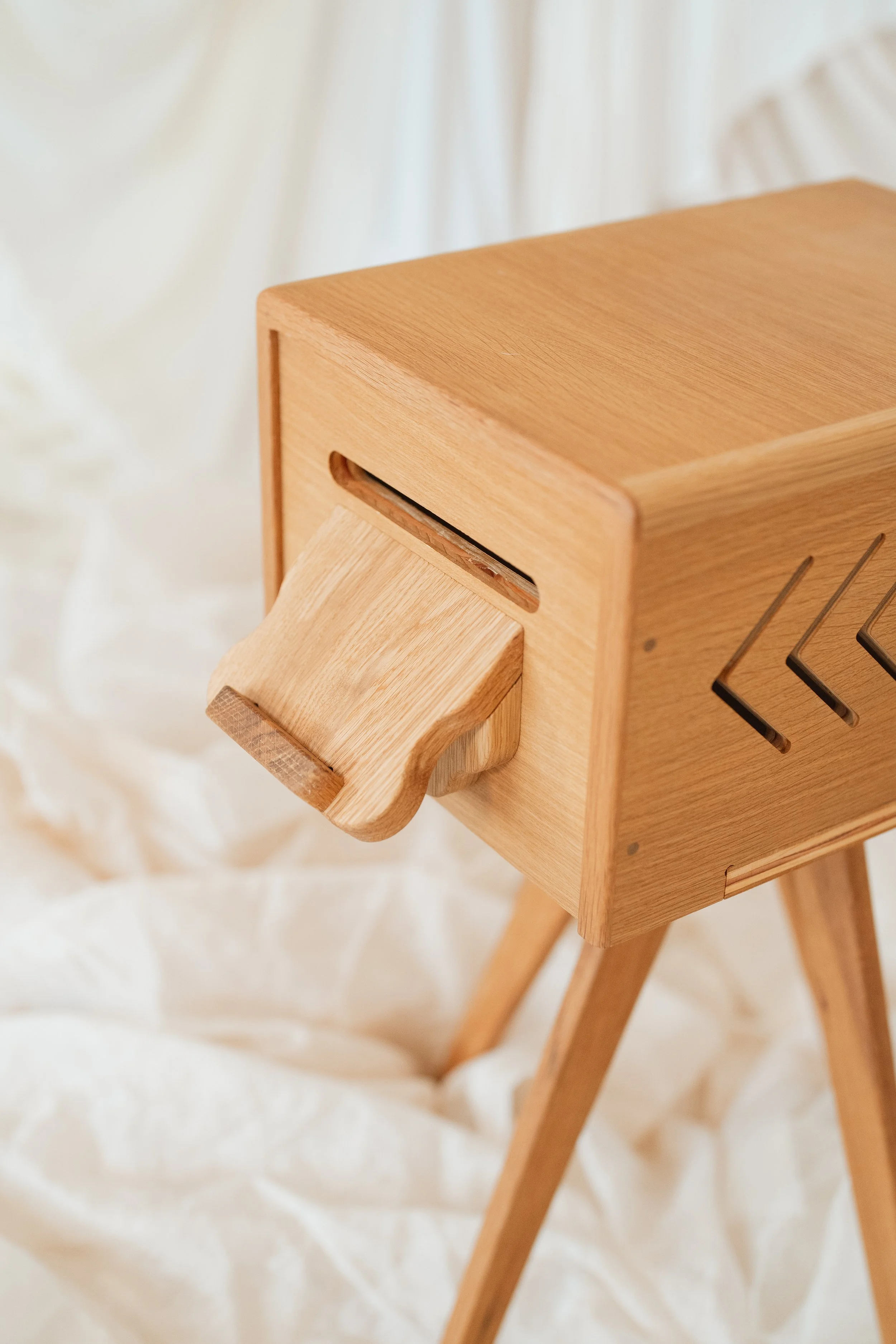 Close-up of a wooden dollhouse with a small attached swing, set against a light background.