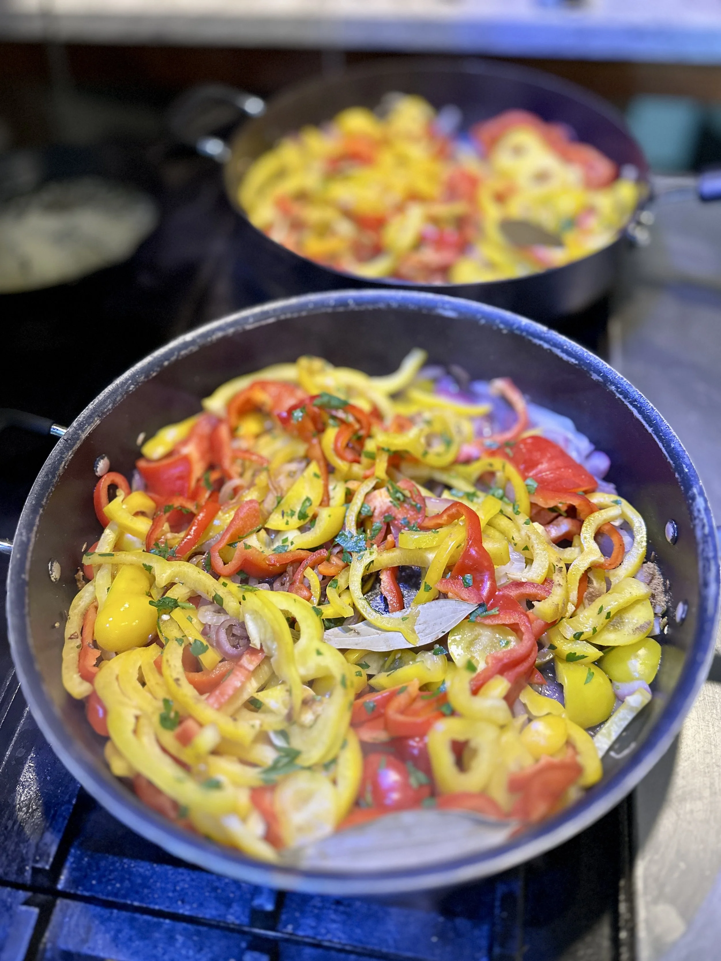 Colorful sautéed bell peppers with herbs in a black skillet.