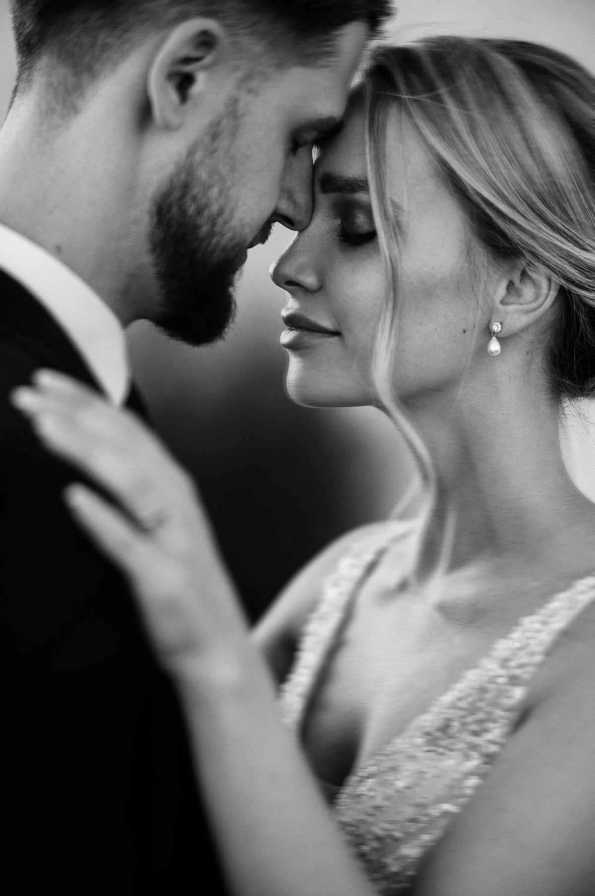 Black and white photo of a couple touching foreheads with eyes closed, emphasizing intimacy and love.