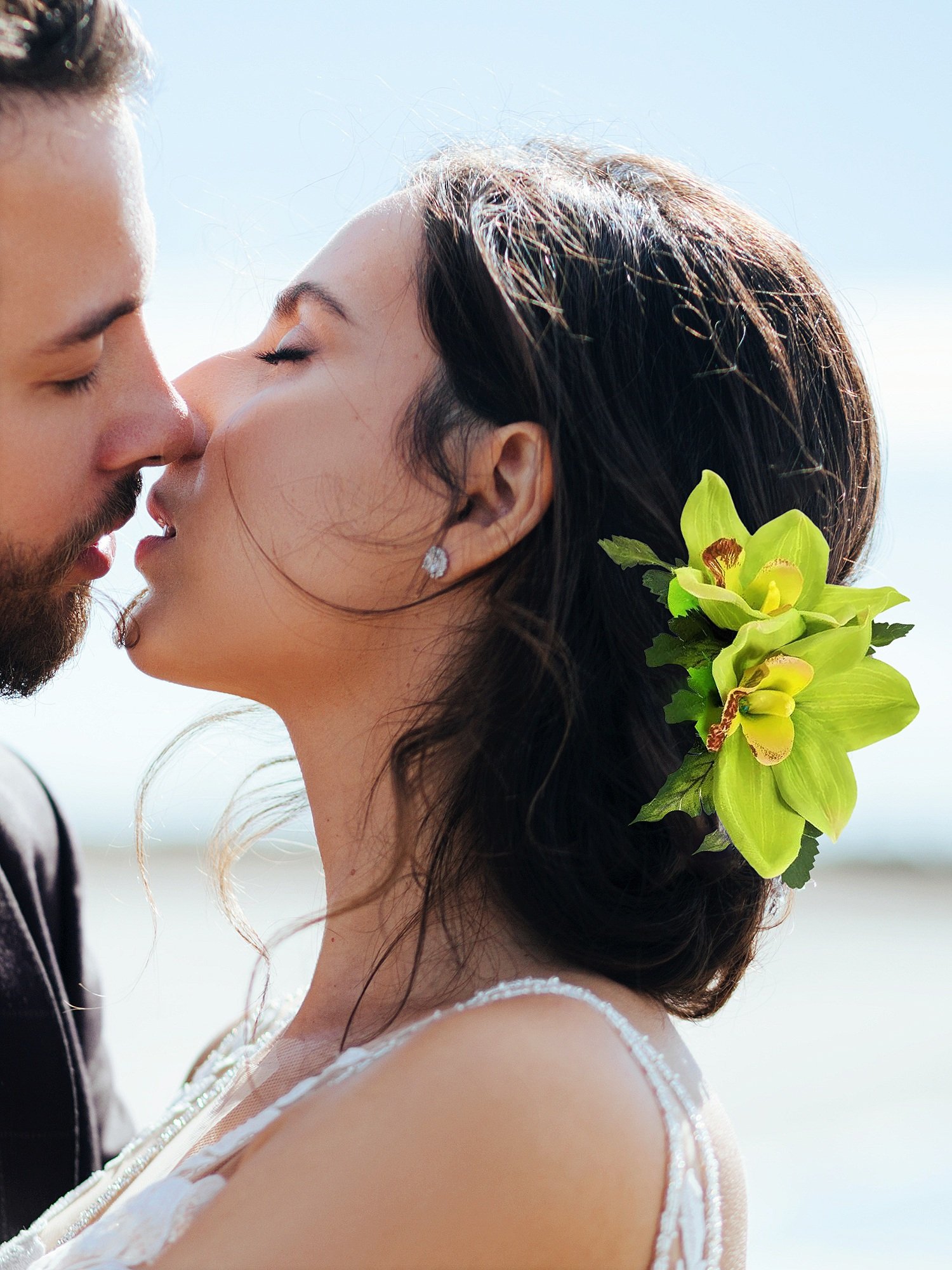 Bride wearing green silk orchids headpiece kissing groom
