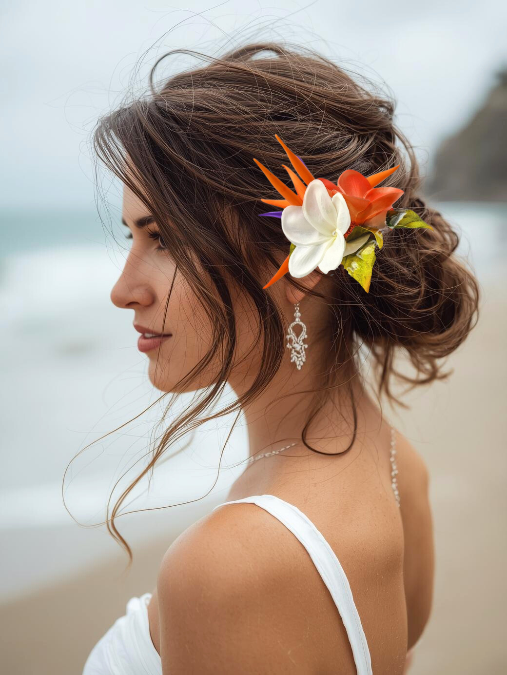 woman on beach wearing a bird of paradise and orange plumeria hair flower clip