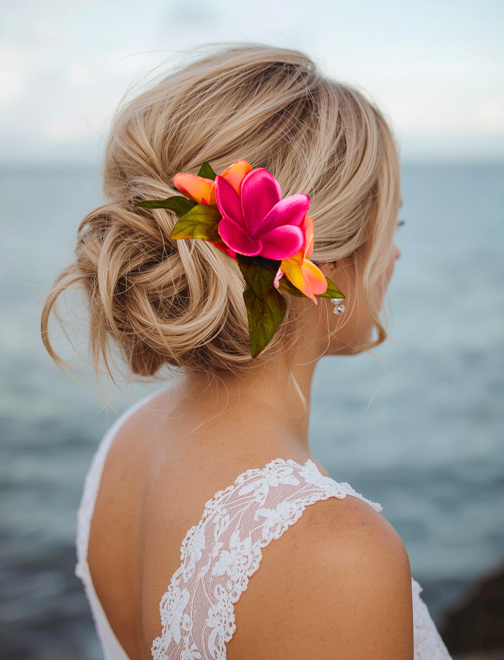woman on beach wearing silk pink rose and sunset plumeria hair accessory