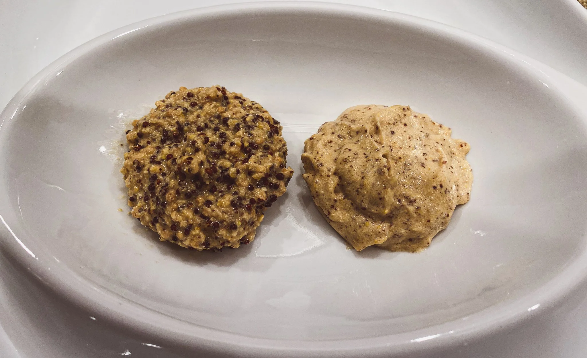 Side-by-side mustards, one hearty one creamy.