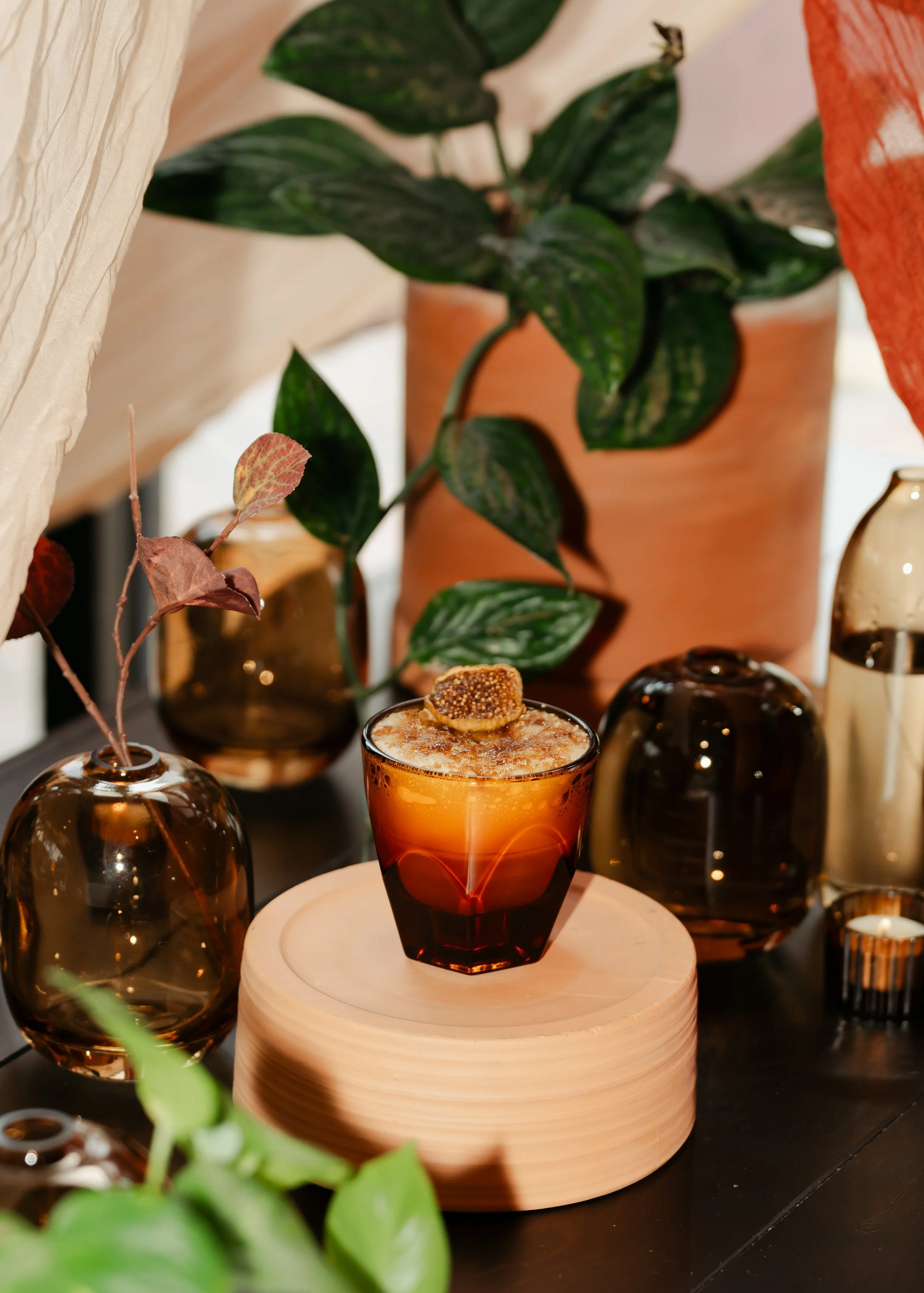 A glass of orange-colored drink spiced with brown sugar fig syrup, espresso, your choice of milk, topped with torched brown sugar and a dried fig. 