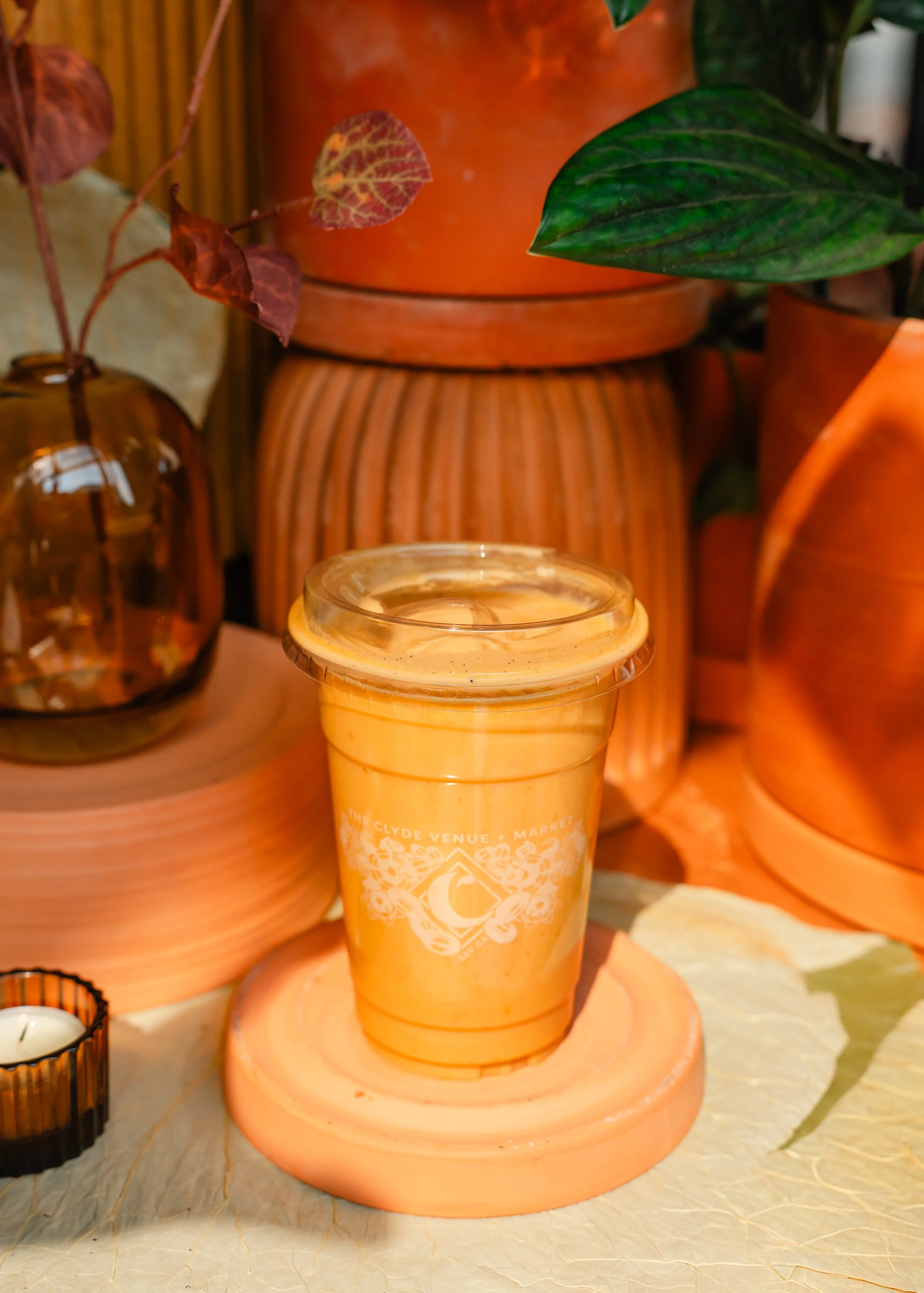 A smoothie beverage in a plastic cup with a clear lid filled with banana, pumpkin, vanilla protein, pumpkin spice, almond milk
