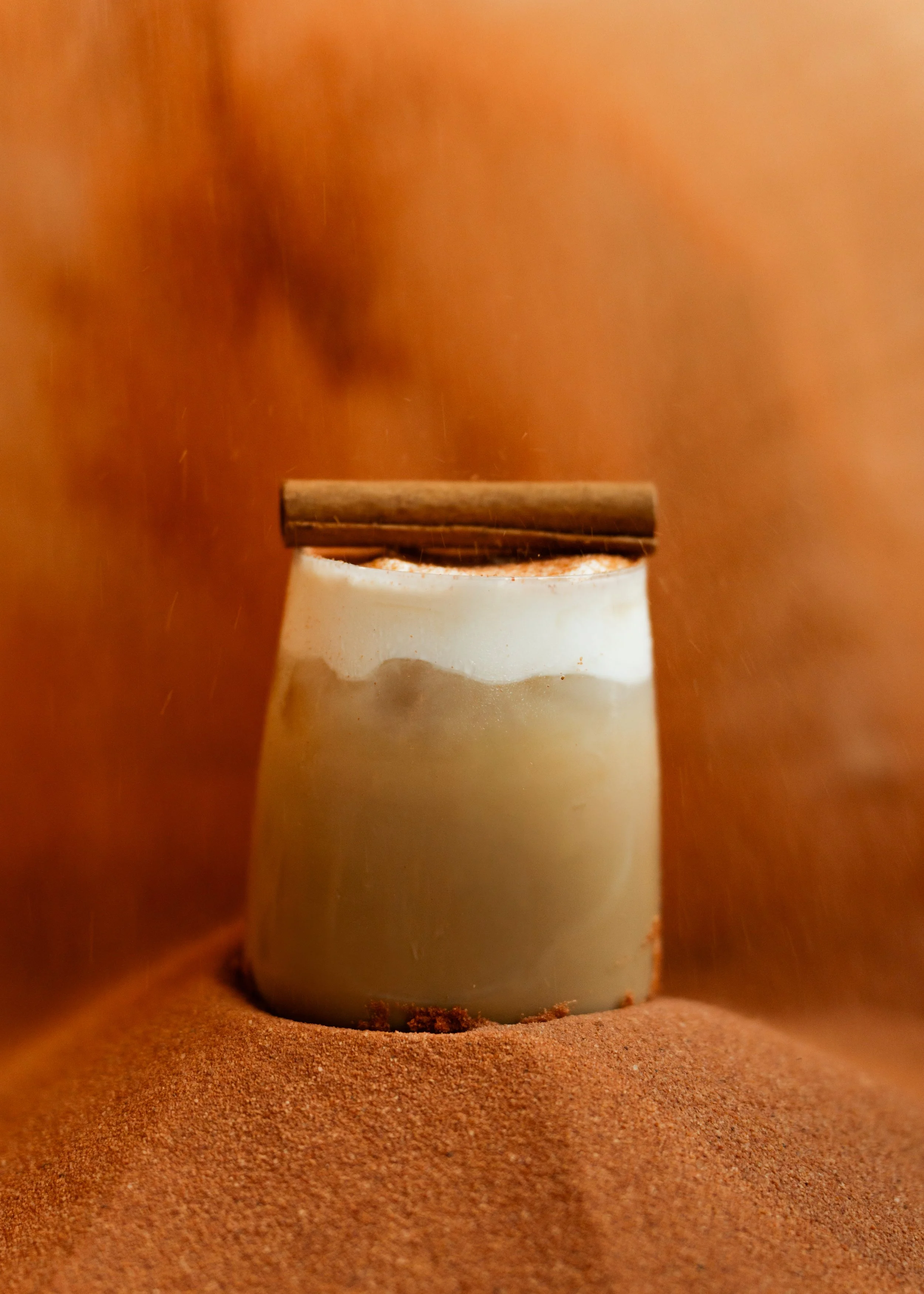 A white ceramic cup filled with HOMEMADE PUMPKIN SPICE SYRUP, ESPRESSO, YOUR CHOICE OF MILK, TOPPED WITH  
(iced) vanilla Cold Foam